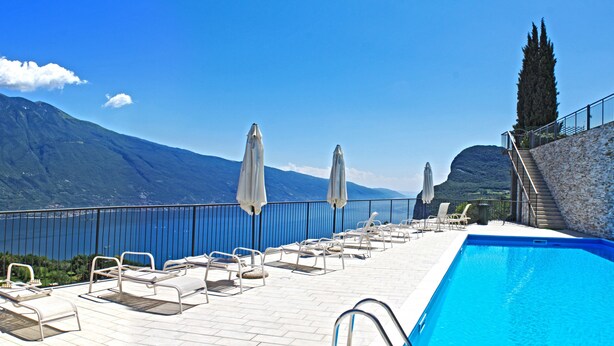 A poolside area with lounge chairs and umbrellas, overlooking a mountainous landscape. - La Quiete 29 Holideal (Tremosine)