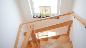 A wooden staircase with a window above, a picture frame with flowers, and seashells on the windowsill. - Apartment Vitko (Nin)