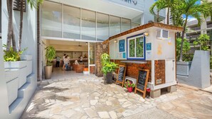A coffee shop with a stone-tiled patio, a signboard, and a small seating area with tables and chairs. - Ocean-Diamond Head Views Condo at Pacific Monarch Hotel Steps to the Beach (Honolulu)
