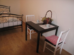 Cozy retreat with a single bed, wooden table, and comfortable seating for two.