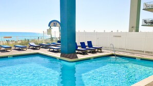 A swimming pool with blue lounge chairs and a lifeguard stand.