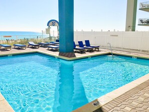 A swimming pool with blue lounge chairs and a lifeguard stand. - 🌞Remodeled-Pool-Grandview East 1601- Azure Paradise🌞 (Panama City Beach)