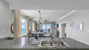 A modern kitchen with granite countertops, stainless steel appliances, and a view of the ocean.