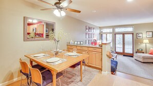 A dining area with a wooden table set for four, a ceiling fan, and a kitchen in the background. - Lake Tahoe Corner Condo w/ Hot Tub, Beaches Nearby (Incline Village)