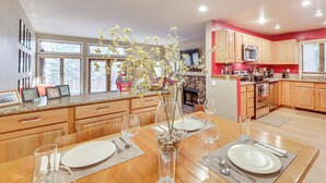 A modern kitchen with wooden cabinets, a dining area with a table set for two, and a vase with flowers. - Lake Tahoe Corner Condo w/ Hot Tub, Beaches Nearby (Incline Village)