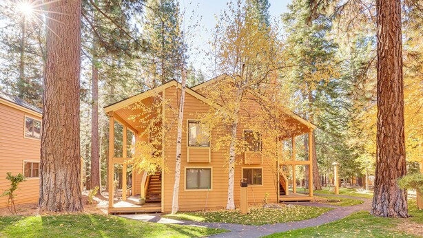 A wooden cabin with a porch, surrounded by tall trees and a clear sky. - Lake Tahoe Corner Condo w/ Hot Tub, Beaches Nearby (Incline Village)