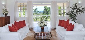 Relax in this stylish room with two sofas, a coffee table, and a large potted plant, offering a view of lush greenery.