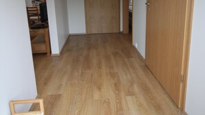 A hallway with wooden flooring, white walls, and a wooden door at the end. - Selfell Guesthouse - Apartment 2 (Kirkjubæjarklaustur)