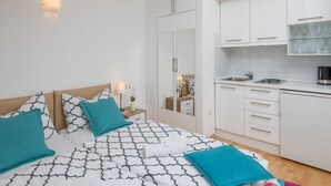 A bedroom with a bed, bedside tables, and a small nightstand with a lamp. - Split Center Suites (Split)