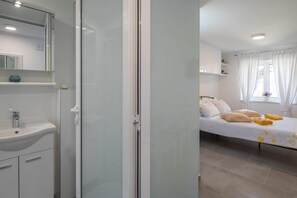 A hotel room with a bathroom, a bed with pillows, and a window with curtains. - Split Center Suites (Split)