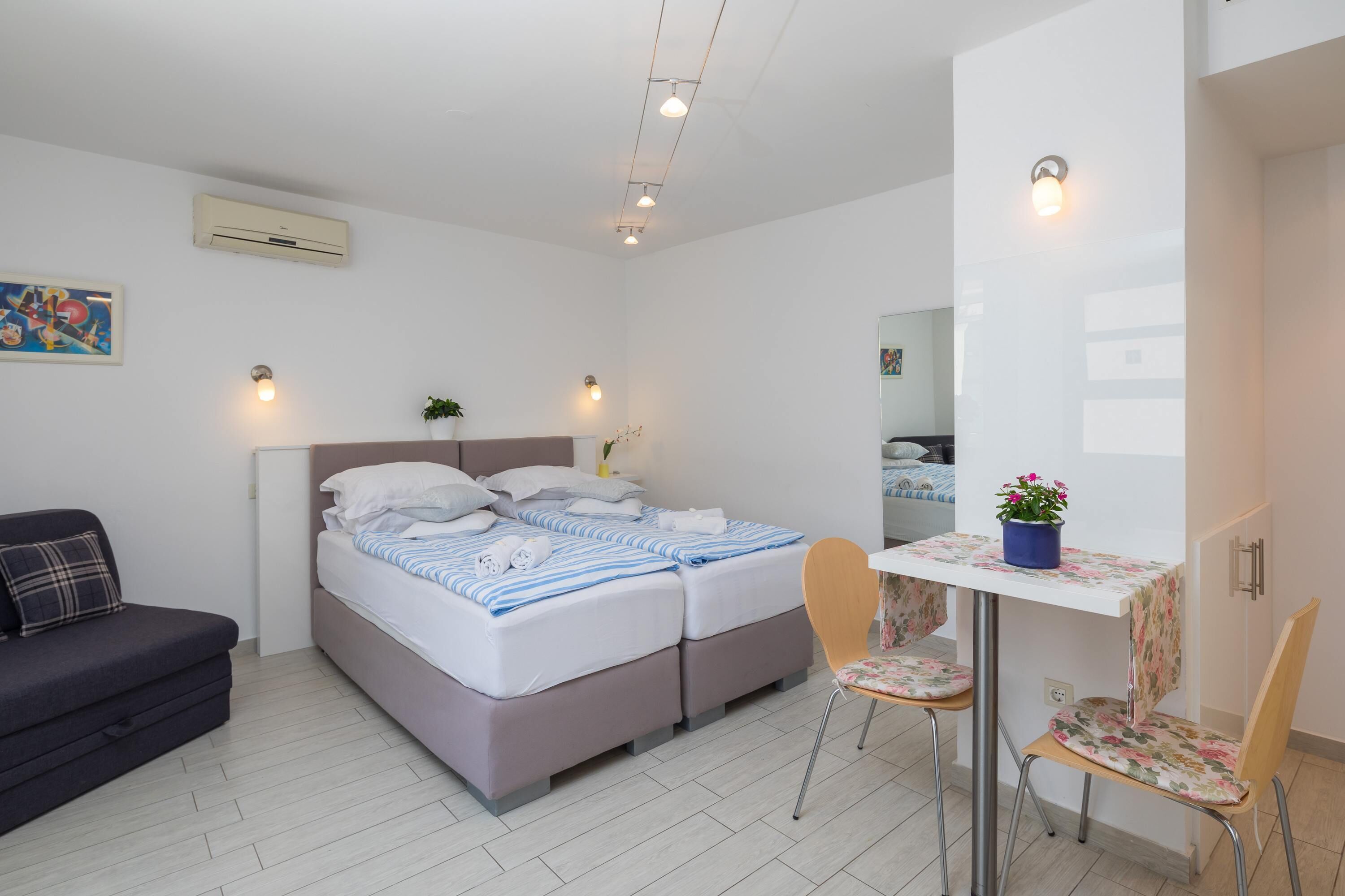 A bedroom with a bed, bedside tables, a desk, a chair, and a couch.
