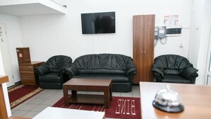 A living room with a black leather sofa, a wooden coffee table, and a TV mounted on the wall. - HOTEL GLOBAL (Bra?ov)