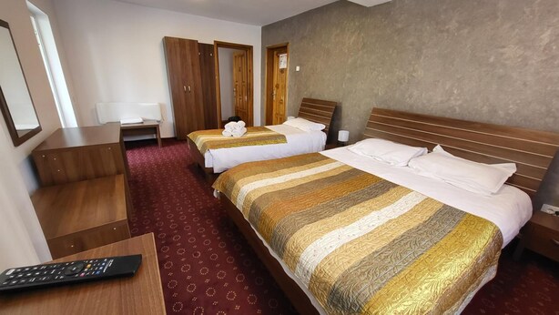 A hotel room with two beds, a desk, a chair, and a TV. - HOTEL GLOBAL (Bra?ov)