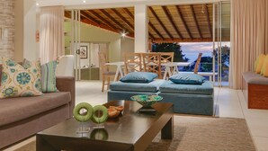 Ein modernes Wohnzimmer mit einer Couch, zwei Hocker, einem Couchtisch und einem Essbereich mit Tisch und Stühlen.