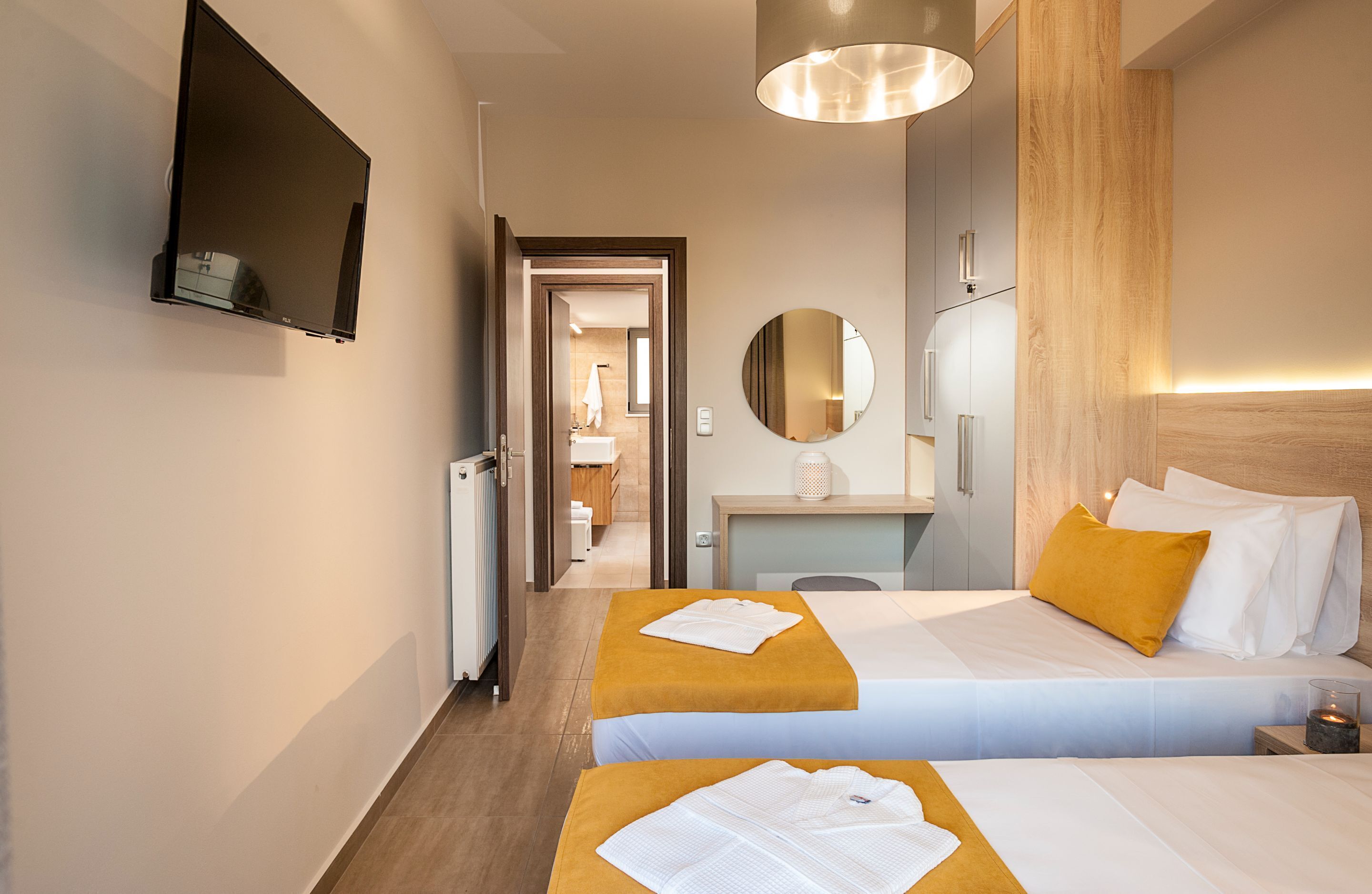Habitación de hotel con dos camas, un escritorio, un espejo y un televisor.