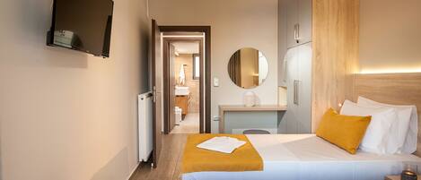 Habitación de hotel con dos camas, un escritorio, un espejo y un televisor.
