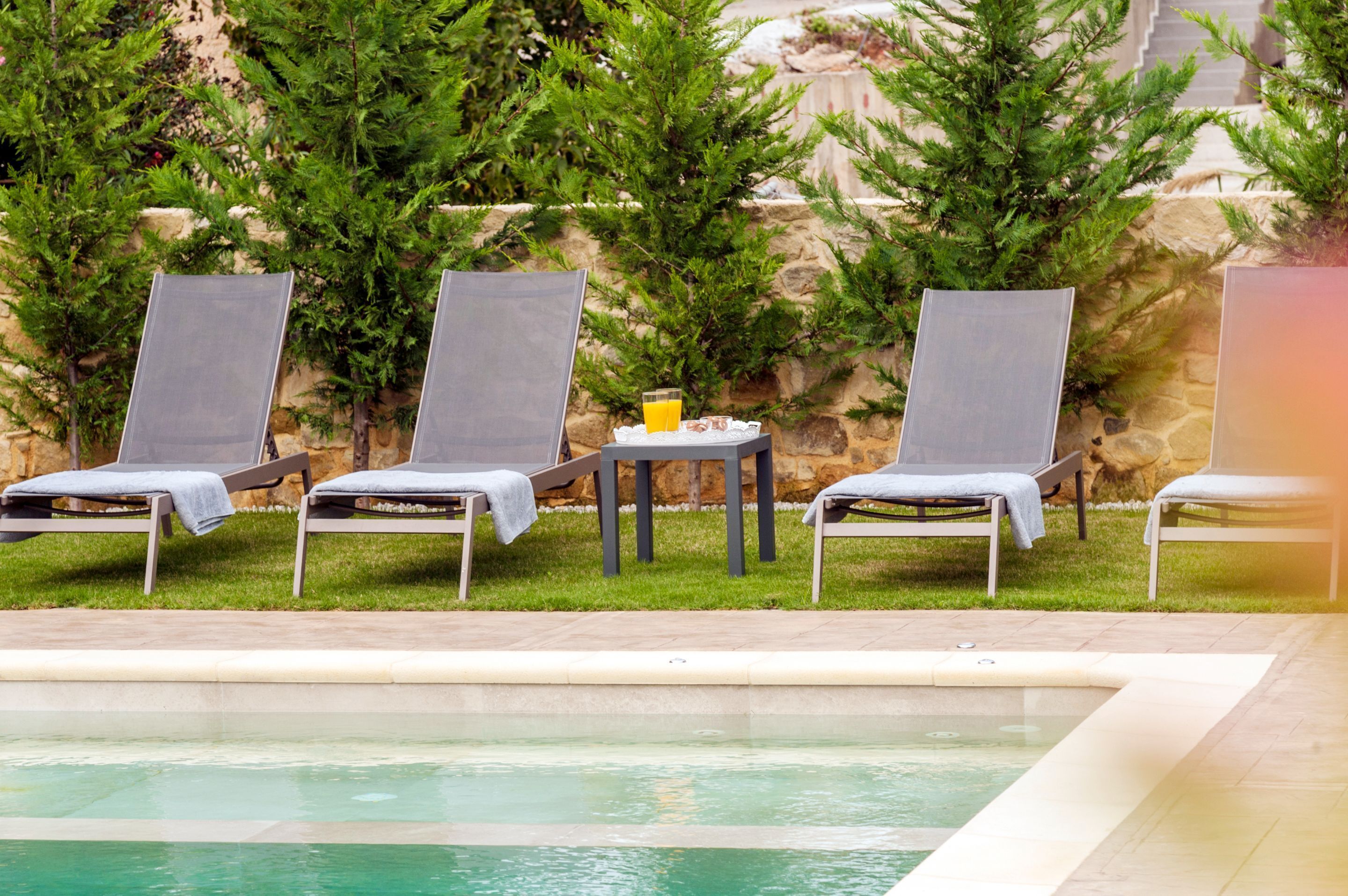Ein Poolbereich mit Liegestühlen und einem Tisch mit einem Getränk.