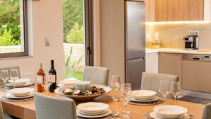 Un espace de restauration moderne avec une table mise pour le repas, un bol rempli de nourriture, des bouteilles de vin et des verres.