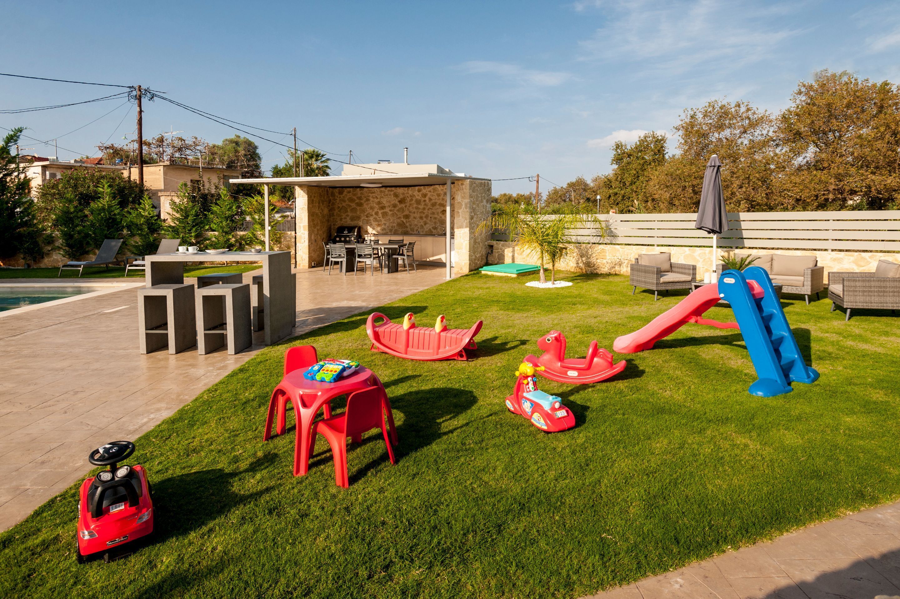 A backyard with a pool, outdoor seating, and children's play equipment.