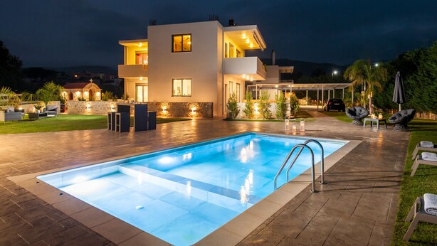 Une maison moderne à deux étages, dotée d’une piscine, d’un espace extérieur aménagé et d’un patio bien éclairé.
