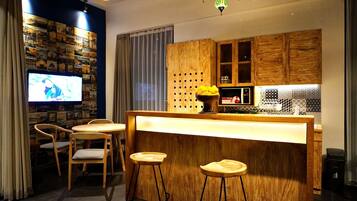 Eine moderne Küche mit Holzausstattung, einer Bar mit Sitzgelegenheiten und einem Fernseher, der ein Programm zeigt.