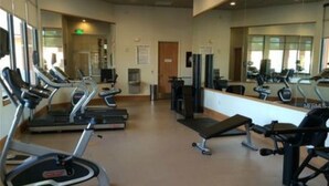 Une salle de sport équipée de plusieurs tapis de course, de machines de musculation et de bancs.
