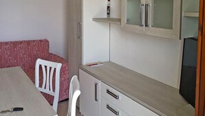 A compact kitchen with white cabinets, a wooden countertop, and a built-in TV. - La Quiete 30 Holideal (Tremosine)
