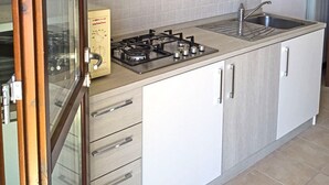 A modern kitchen with light wood cabinets, a stainless steel sink, and a gas stove. - La Quiete 30 Holideal (Tremosine)