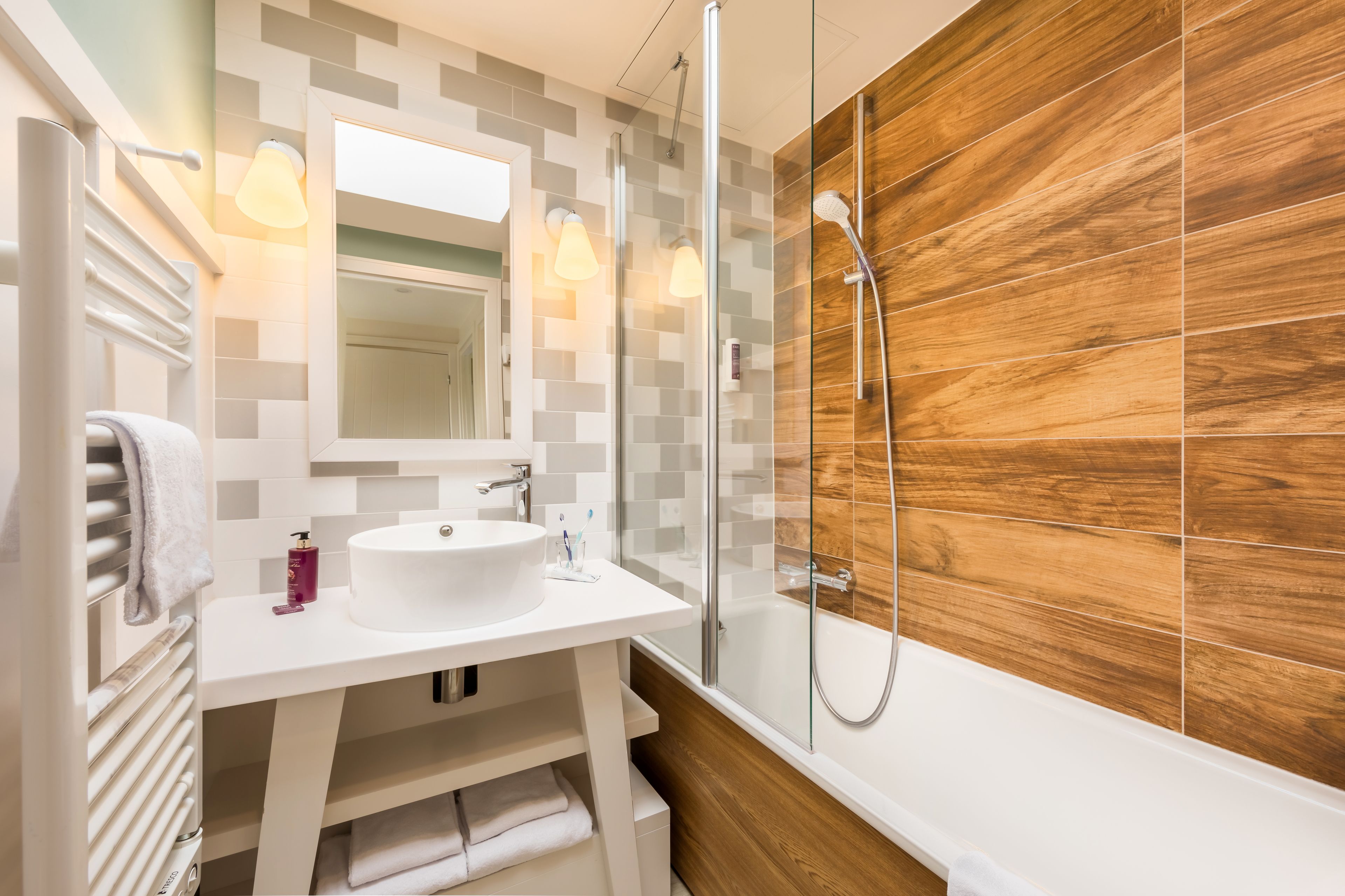 A modern bathroom with a white sink, mirror, and glass shower enclosure.