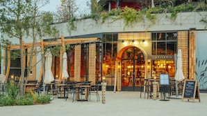 An outdoor café with tables and chairs, a sign reading "Café", and a menu board outside. - Les Villages Nature Paris (Villeneuve-le-Comte)