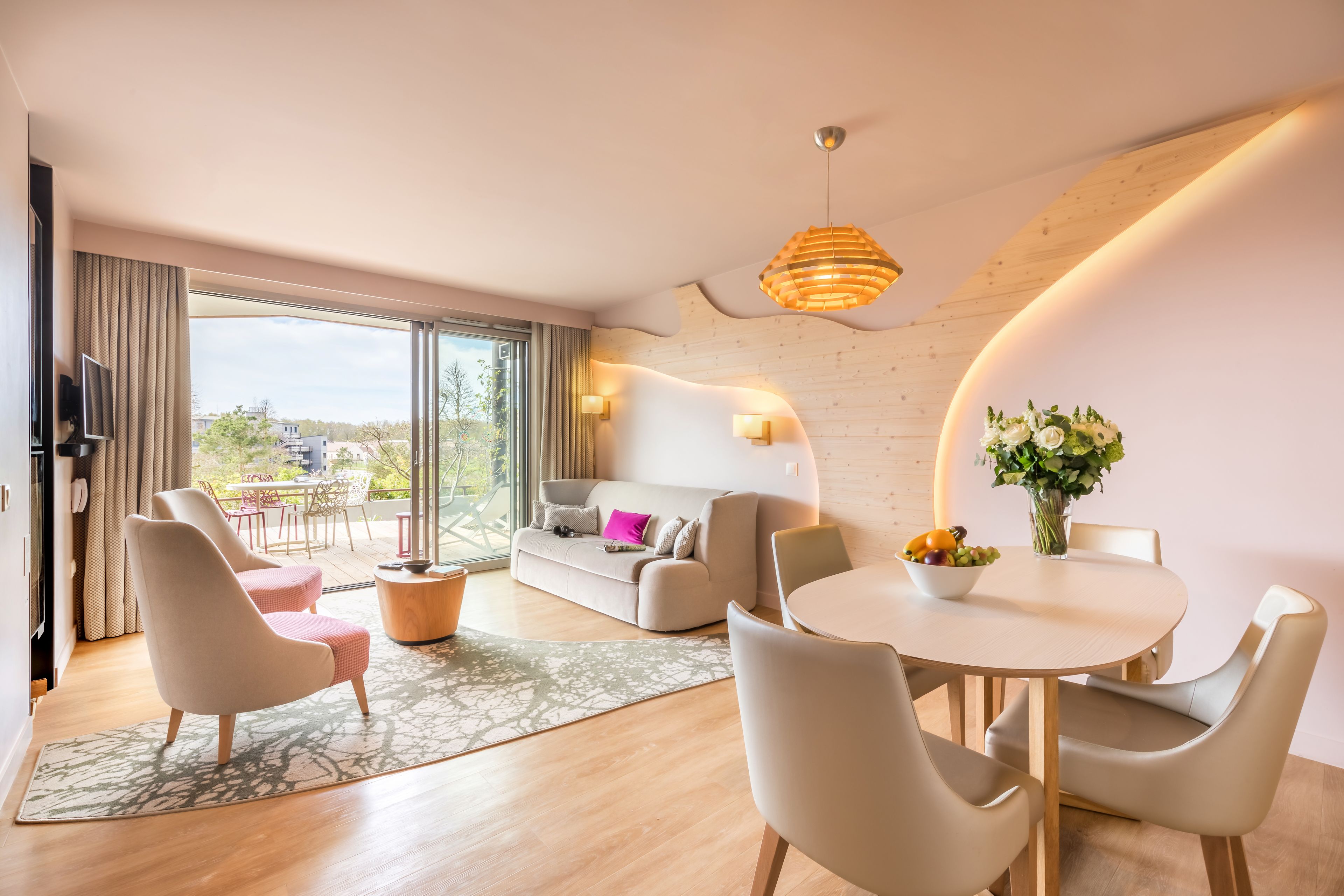 A modern living room with a sofa, chairs, a dining table, and a large window.