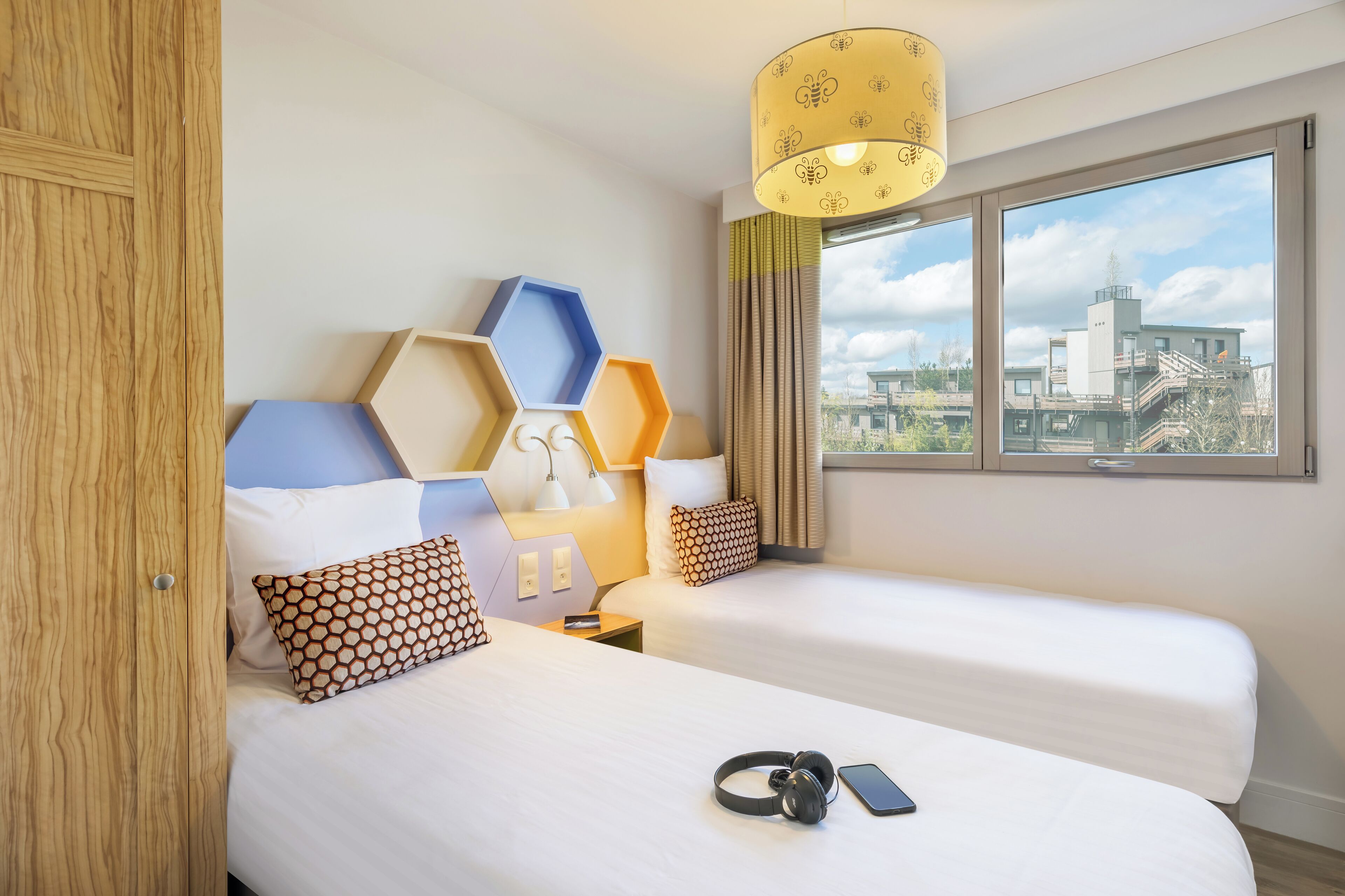 A hotel room with two beds, a city view, and a modern design.
