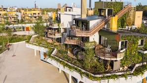 A modern building with multiple balconies, a staircase, and a rooftop garden. - Les Villages Nature Paris (Villeneuve-le-Comte)
