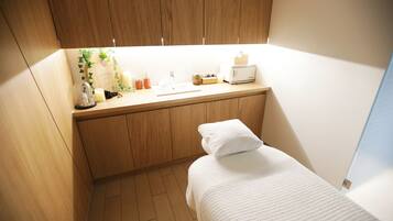 A compact room with a wooden cabinet, a small sink, a bed with a white pillow, and a window.