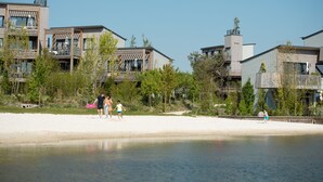 A beachfront property with modern architecture, including multiple balconies and large windows. - Les Villages Nature Paris (Villeneuve-le-Comte)