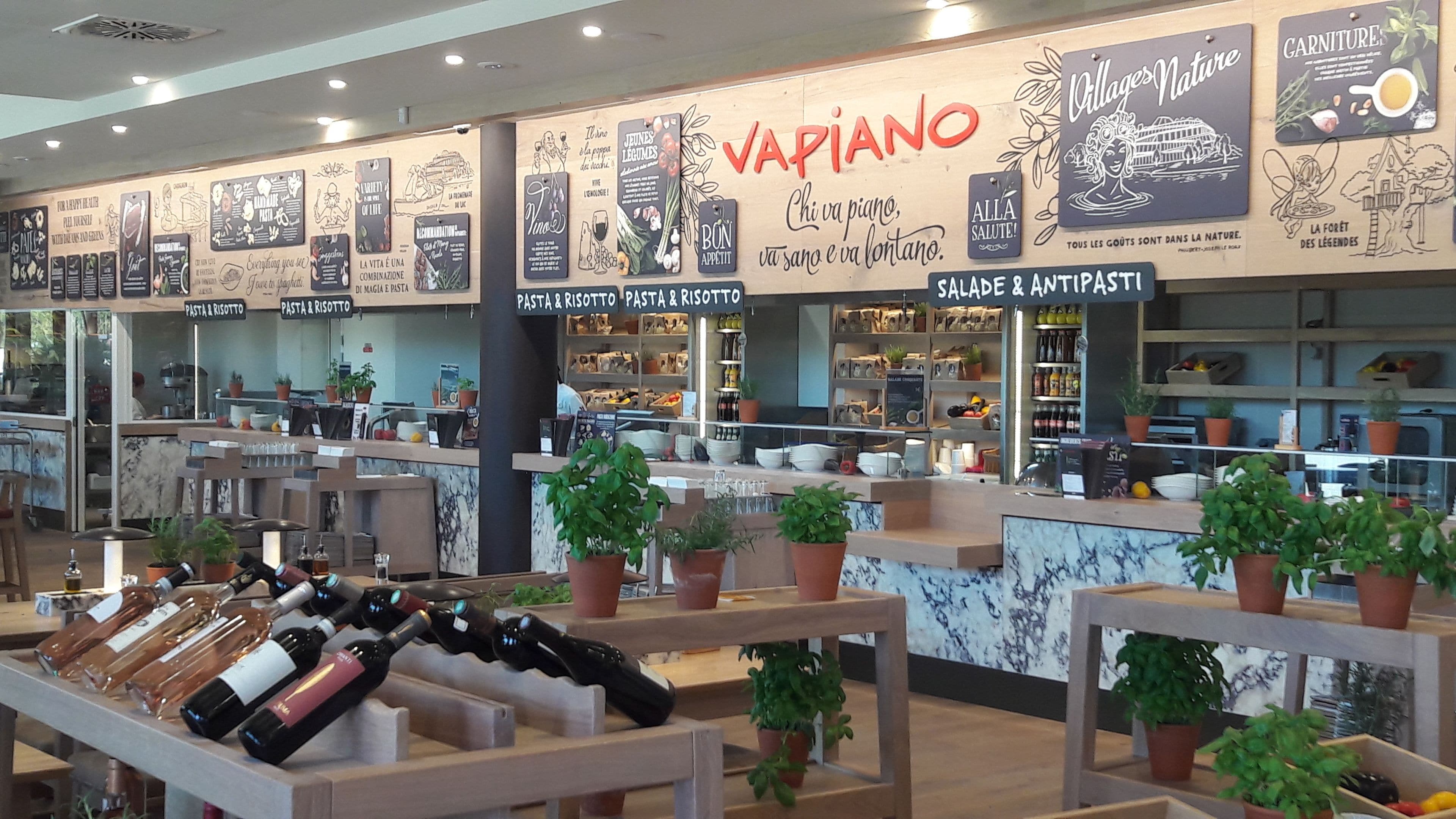 A restaurant interior with a variety of pasta and risotto dishes displayed on the counter.