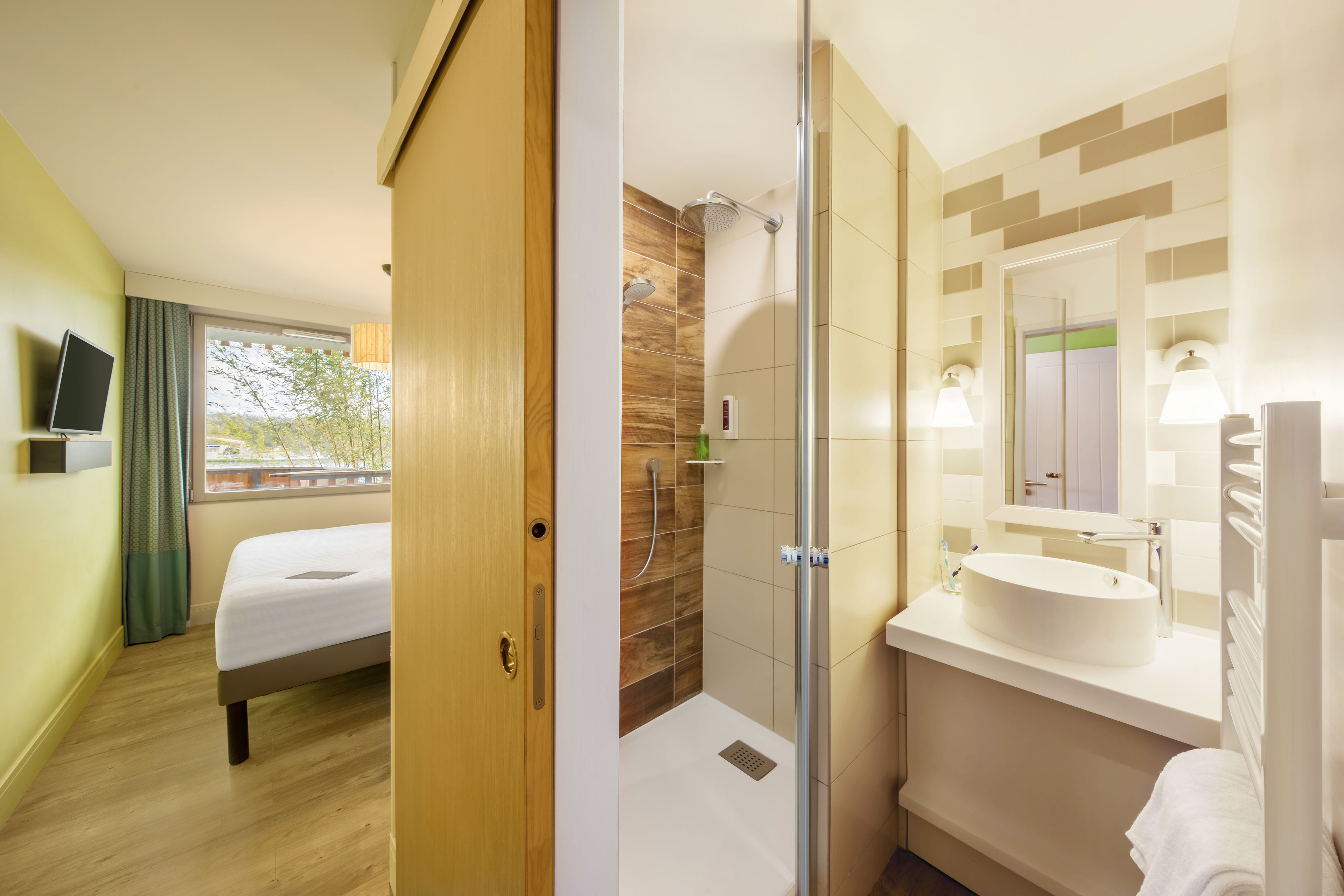 Une chambre d’hôtel équipée d’un lit, d’une douche, d’un lavabo et d’une télévision.