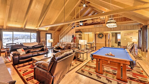 A spacious living room with a pool table, leather sofas, and a high ceiling with wooden beams. - Centennial Cabin w/ Hot Tub, Sauna & Pool Table! (Centennial)