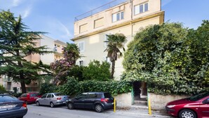 A multi-story residential building with a balcony, parked cars, and lush greenery. - Apartment Signorina Leticija (Split)