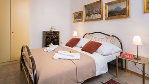 A neatly made bed with white and brown linens, a bedside table with a lamp, and a small cabinet with decorative items. - Apartment Signorina Leticija (Split)
