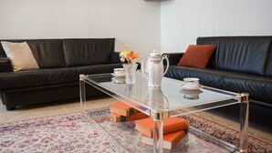 A living room with a glass coffee table, black leather sofas, a patterned rug, and books. - Apartment Signorina Leticija (Split)