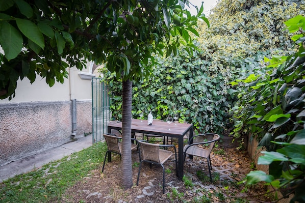 Relax in a serene outdoor space surrounded by lush greenery and a tree, with a table and four chairs.