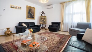 A living room with a glass coffee table, two sofas, a chandelier, and a large window with curtains. - Apartment Signorina Leticija (Split)
