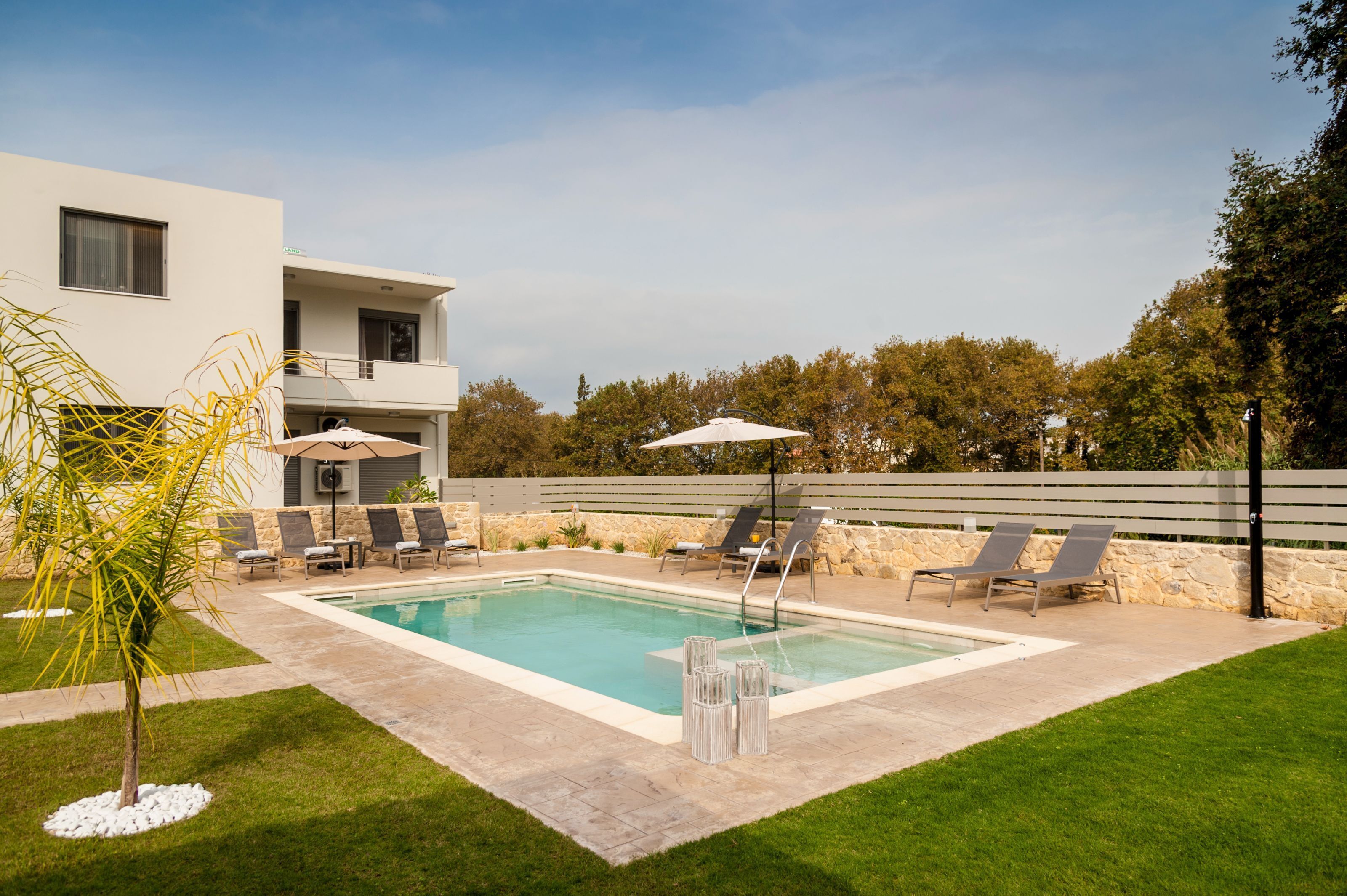 A modern pool area with a rectangular pool, lounge chairs, and umbrellas.