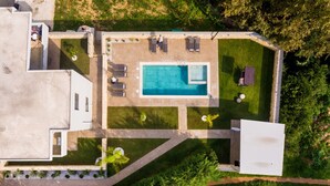 An aerial view of a modern house with a swimming pool, outdoor seating, and a well-maintained garden. - Kagiemar Luxury House (Chania)