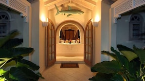 A hallway with a shark decoration, a wooden door, and a tiled floor. - Villa Oceana (Holetown)