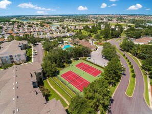 An aerial view of a residential area with a tennis court, a swimming pool, and a curved road. - Windsor Palms Resort by ITSVR (Kissimmee)