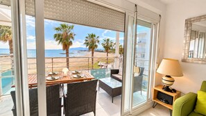 Balcón con mesa lista para comer, con vista a la playa y la piscina.