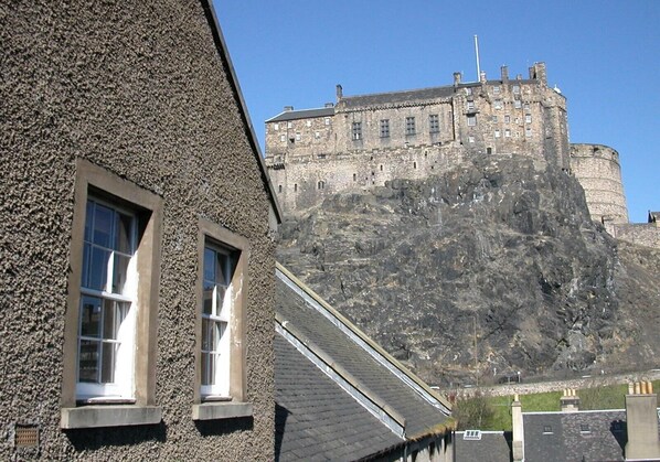 A building with two windows and a stone wall.