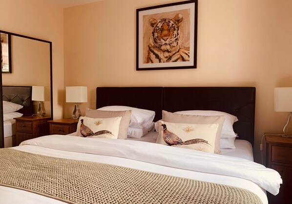 A hotel room with a large bed, two bedside tables with lamps, a framed tiger painting on the wall, and decorative pillows.